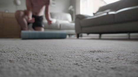 a man rolling out a yoga mat in his living room at home