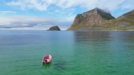 boat floats in arctic sea at summer in haukland beach, lofoten islands, norway - aerial 4k circling