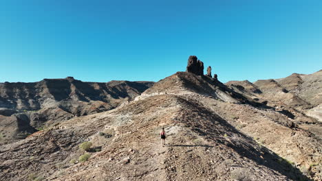 Aerial-tracking-of-a-young-woman-with-long-hair-heading-towards-a-large-rock-formation-near-the-Medio-Almud-beach-on-the-island-of-Gran-Canaria