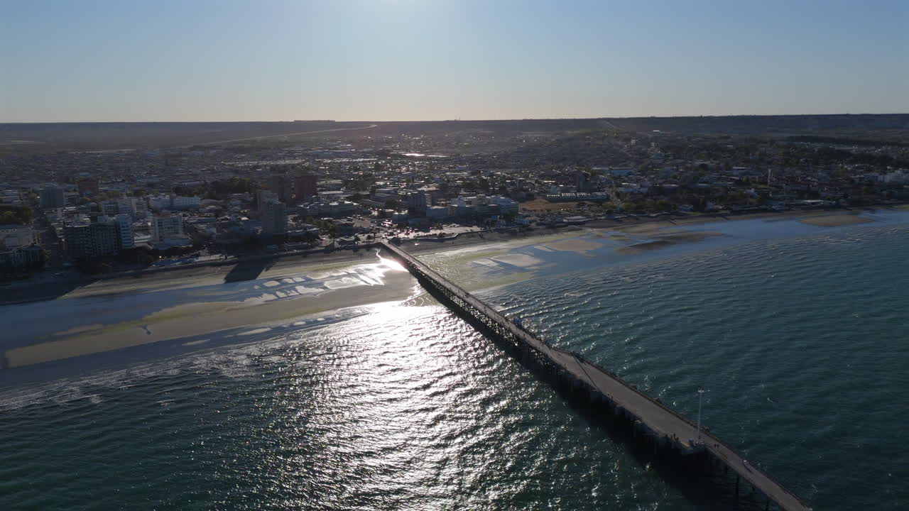 Reverse aerial of town of Puerto Madryn, Argentina with long pier in the water