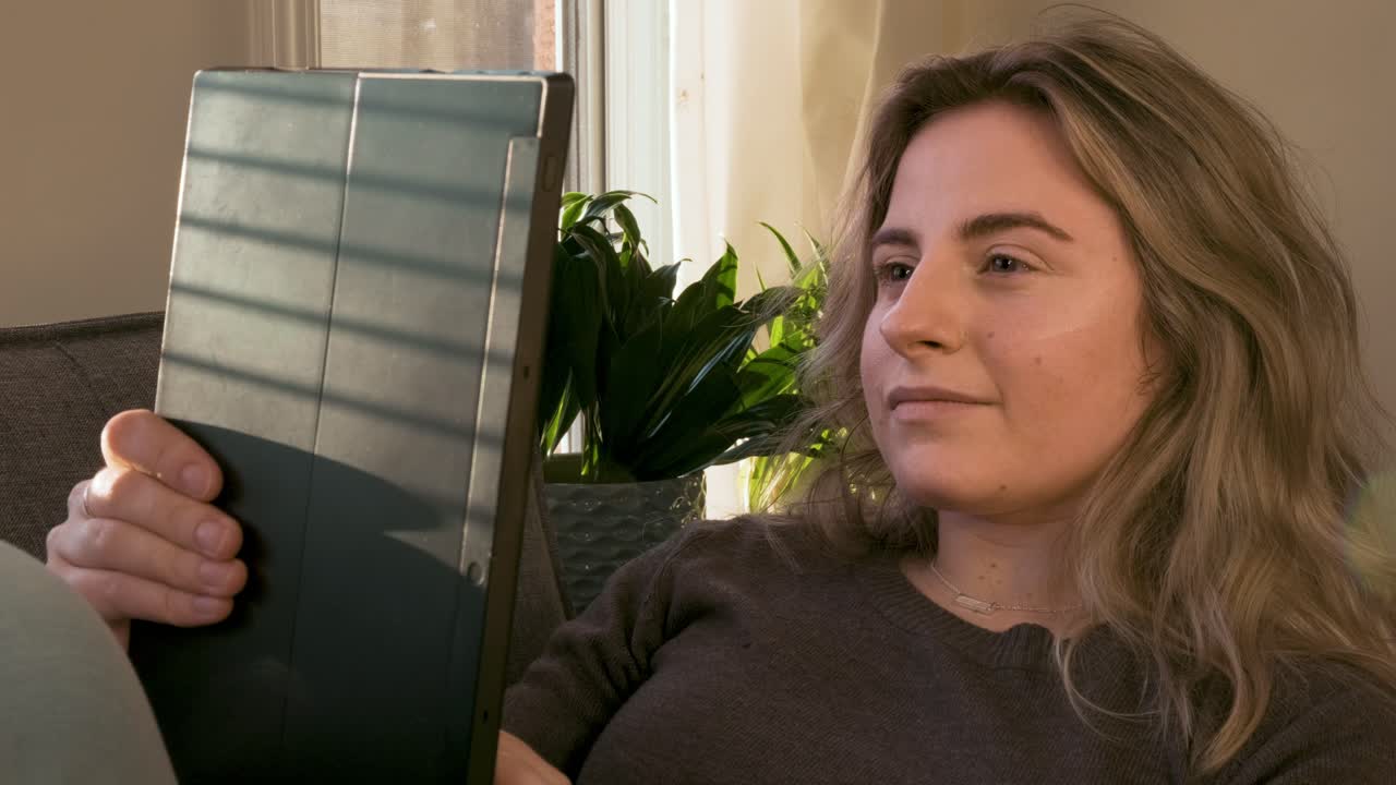 Medium shot of a young woman scrolling through a tablet