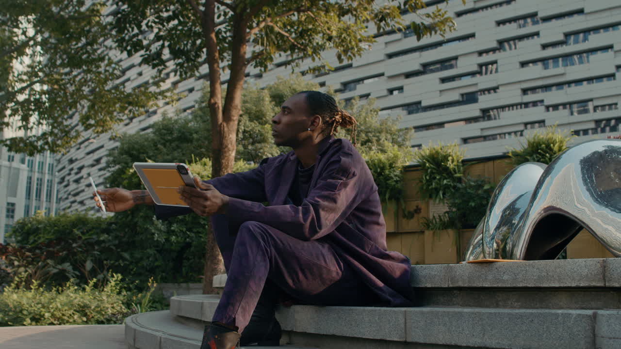 Black man with touchpad looking for inspiration outside in park