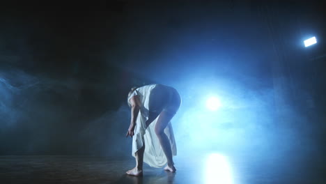 slow-motion: female dancer on stage in smoke. modern ballet barefoot on stage.