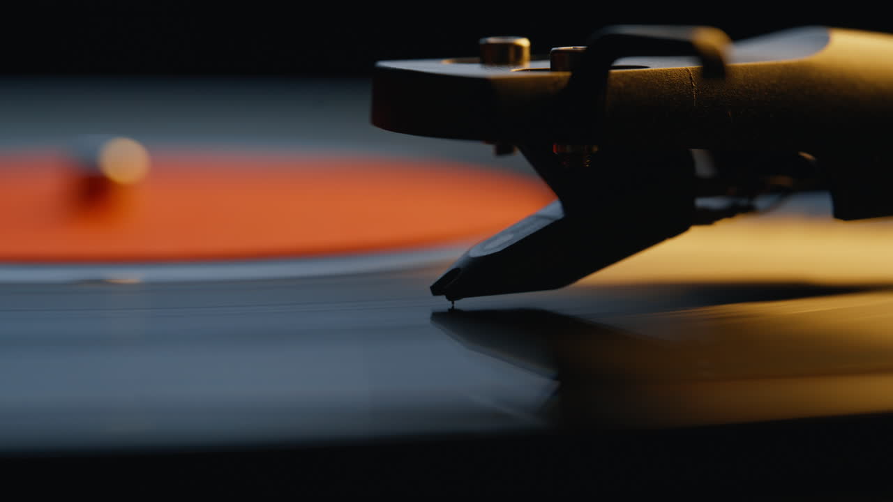 Closeup needle touching vinyl starting playing melody in dark room. Macro stylus