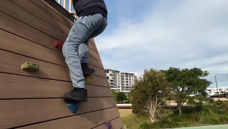 un niño sube una pared de roca ubicada en un parque público en australia