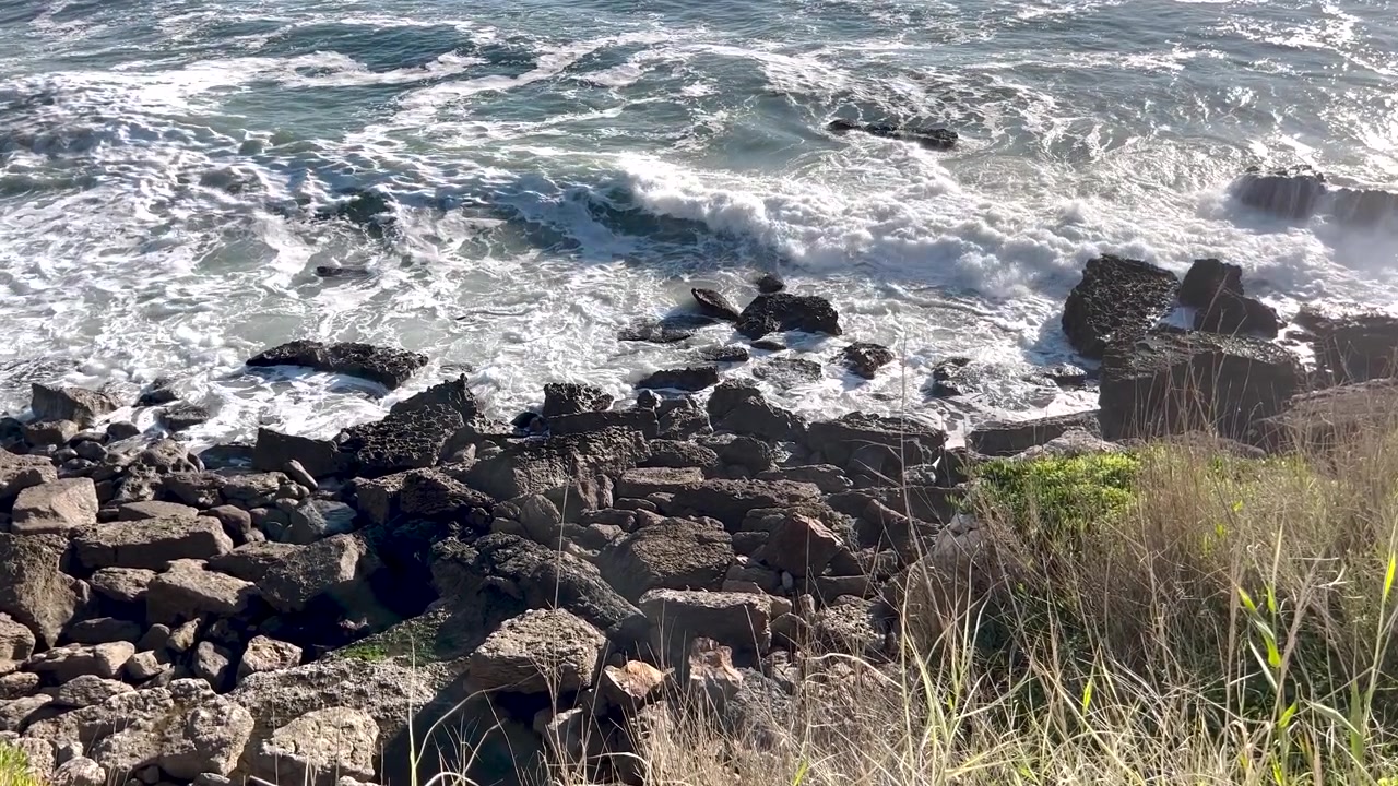 晴れた明るい日、リスボン近郊の岩の海岸に打ち寄せる力強い海の波。ポルトガル沿岸の美しさ、エネルギー、雰囲気を捉える。