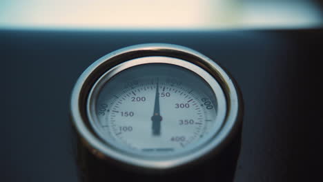 barbecue lid closes, revealing thermometer as temperature drops