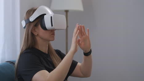 una mujer joven con una pantalla hmd en la cabeza está viendo fotos en realidad virtual gesticulando las manos para hacer zoom en el retrato de la imagen en el interior