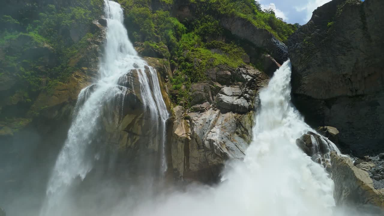 Câmera de drone descendo ao longo do poderoso fluxo da cachoeira Cascada de Agoyan, revelando a escala massiva das paredes rochosas do cânion em Baños, Equador
