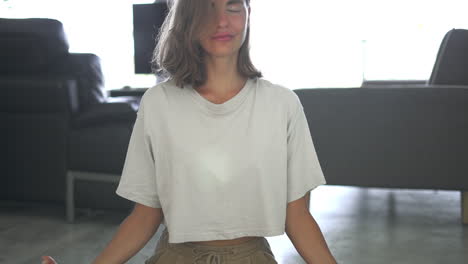view close up of happy smiling woman with closed eyes sitting in lotus pose in living room