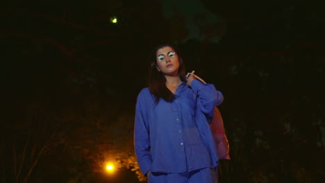 mujer de moda sosteniendo una bolsa de basura después de la limpieza del parque bajo el resplandor de la linterna nocturna