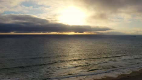 Cielo-Brillante-Al-Atardecer-Brillando-Sobre-El-Mar-En-Calma-Y-La-Playa-Vacía