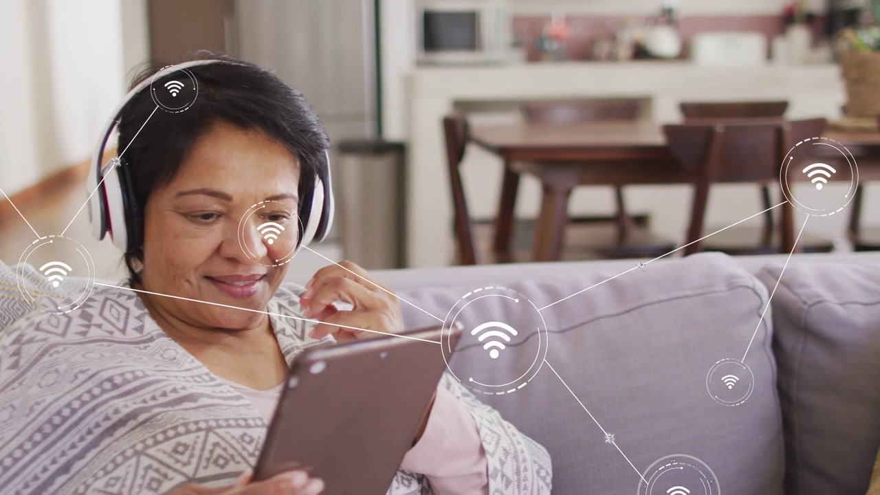 Senior woman tapping tablet, starting Wi-Fi icons growing and linking across room, testing network