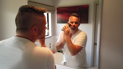 man-with-an-electric-razor-in-the-mirror-shaving-Just-touching-up-a-few-spots,-morning-shave-in-the-mirror-with-electric-razor