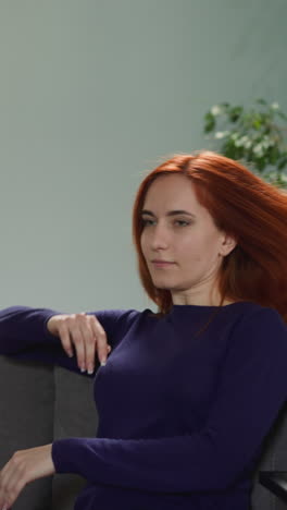 redhead woman comes to sit on comfortable sofa thinking about life. pensive housewife rests in living room after routine chores closeup slow motion