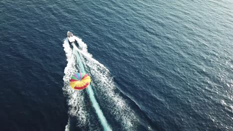 toma aérea de un barco arrastrando un paracaídas en el mar