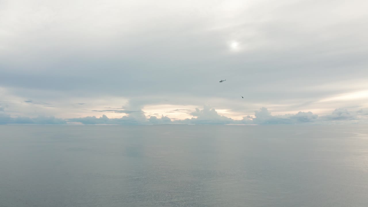 탁 트인 바다 위의 공중을 날아다니는 보급품을 매달아 놓은 헬리콥터, 공중