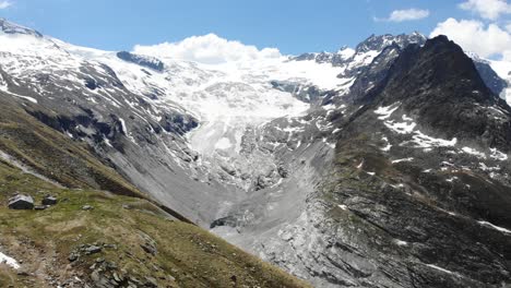 aerial flyover towards the ferpecle glacier in valais, switzerland on a sunny summer day, revealing the the distance that the glacier has receded due to melting as seen by the moraines