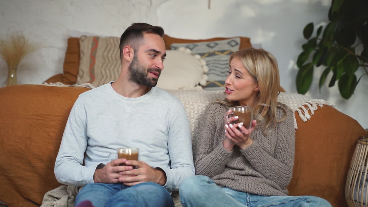 Dejligt par har en samtale og en kop varm chokolade siddende på soveværelsesgulvet på en vinterdag