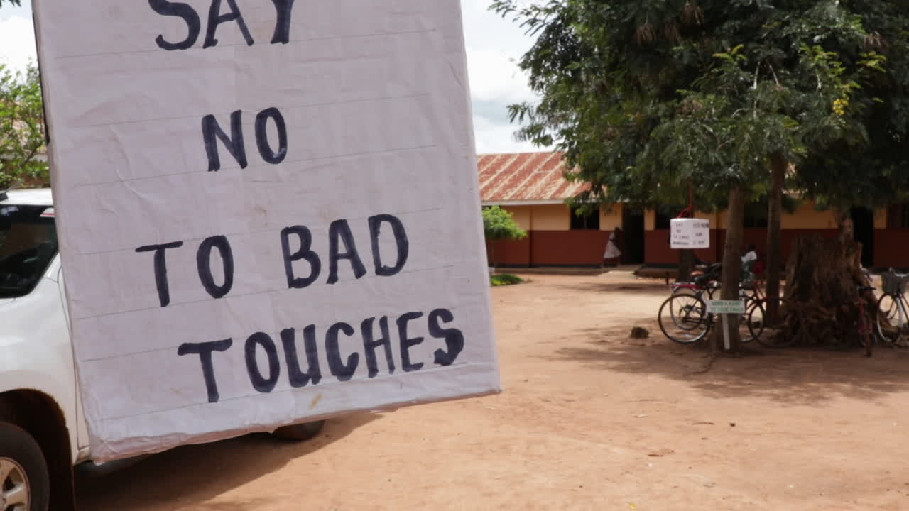 letrero en un patio de una escuela en kampala, uganda, que dice "el sida es real" y otras cosas para crear conciencia