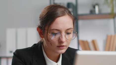 Close-up-businesswoman-freelancer-at-office-workplace-works-on-laptop-computer-sends-online-messages