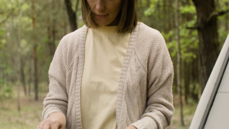 frau, die auf dem grill auf dem campingplatz im wald kocht