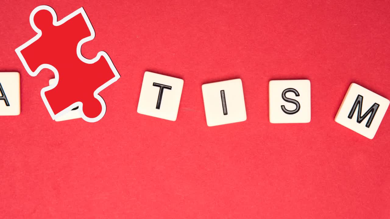 Animation of red and yellow puzzle pieces falling over autism text on squares on red background