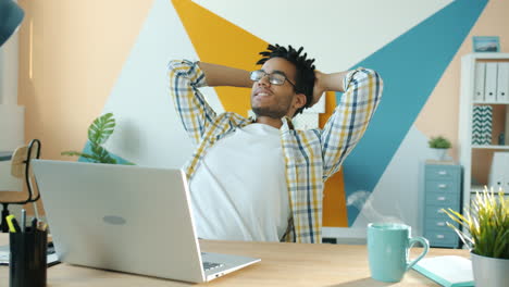 man relaxing at his desk with a laptop