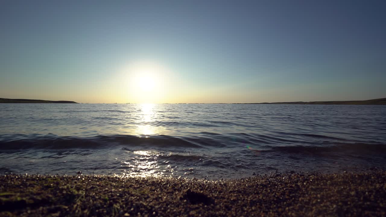 Calm waves lick the shore during sunset over Bitter Lake in South Dakota