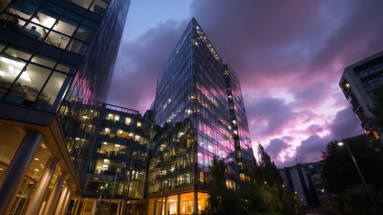 Vista deslumbrante ao entardecer de edifícios de vidro modernos sob céus coloridos, com janelas iluminadas e nuvens vibrantes ao anoitecer em um ambiente urbano