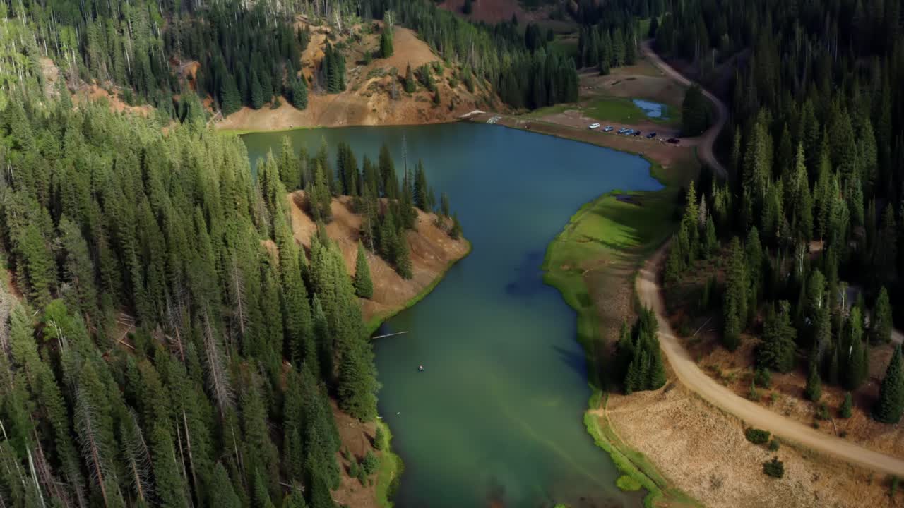 hermoso tiro aéreo inclinado hacia abajo de un impresionante paisaje natural del lago del embalse del prado anderson hasta el cañón del castor en utah con un gran bosque de pinos y un estacionamiento para pescadores