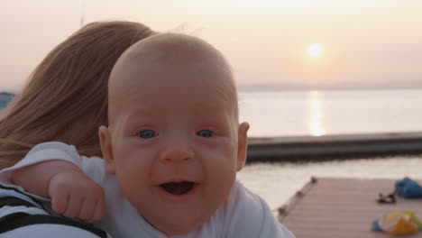 baby girl in mothers hands outdoor at sunset