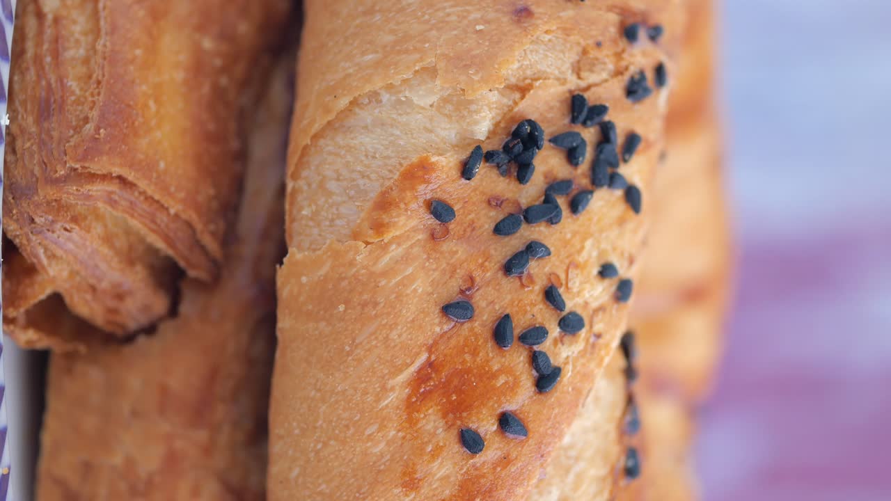 Close-up of golden brown savory pastries topped with black seeds