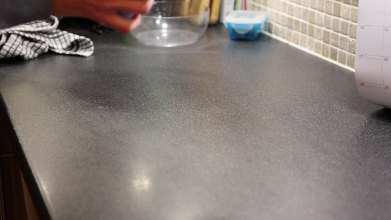 Nærbillede af en kok, der spreder mel ud på en bordplade.