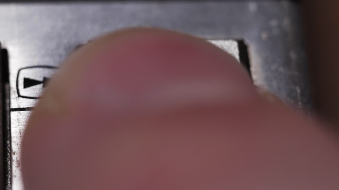 Macro de cerca de un dedo pulsando un botón plateado de avance rápido con doble triángulo
