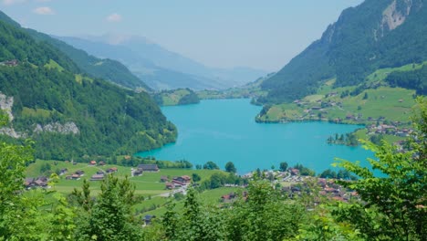 beautiful blue lake in switzerland, surrounded by mountains and green grass, on a clear sunny day