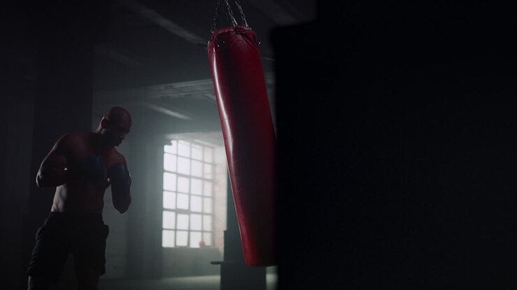 Uomo afroamericano che si allena al sacco da boxe in palestra. Sportivo che colpisce il sacco.