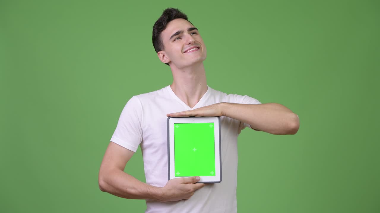 Young handsome man thinking while showing digital tablet