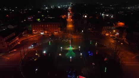 aerial night view of a roundabout with a lit christmas tree and colorful festive lights in an american town