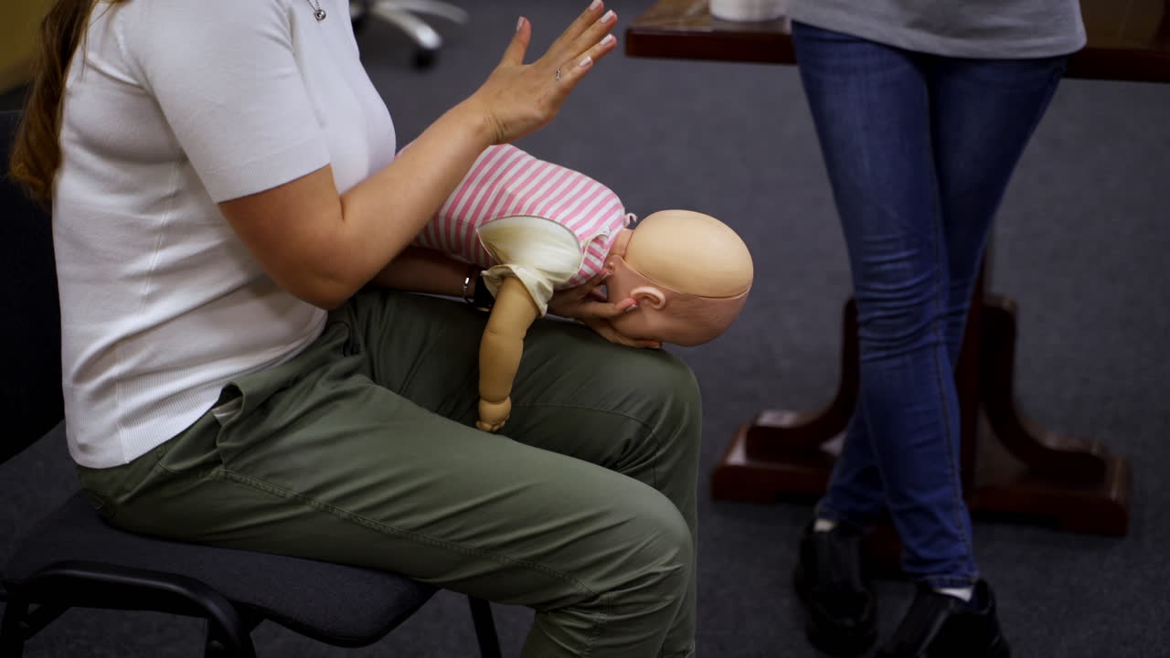 Practical course on a doll dummy. Female practitioner teaching to reanimate patient on a baby mannequine. Instructor demonstrate the training exercise.
