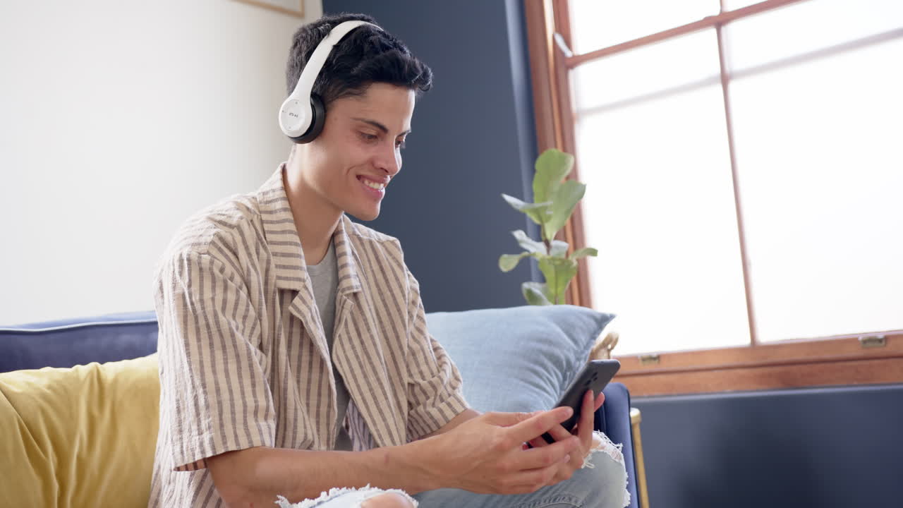 Felice uomo birazziale che indossa cuffie e fa una videochiamata sullo smartphone, spazio per il testo, al rallentatore.