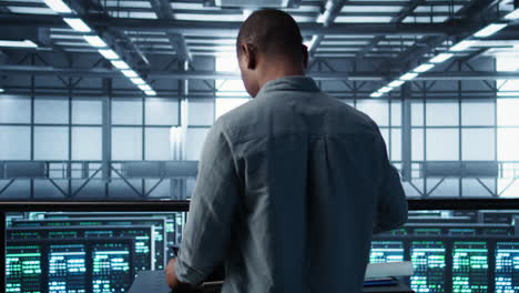 Engineer in data center coding on laptop, optimizing resource utilization