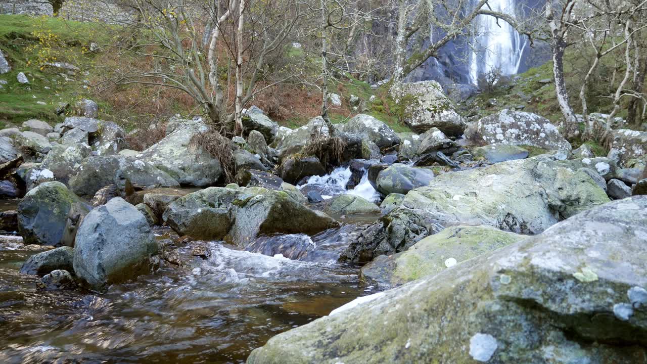 cascada idílica del bosque de montaña que fluye hacia el desierto de cantos rodados irregulares del río dolly a la derecha