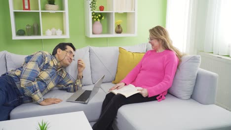 Happy-mature-couple-sitting-on-sofa-at-home,-enjoying-retirement,-carefree-and-relaxed.