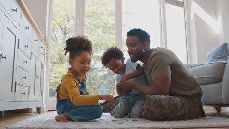 Army-Father-In-Uniform-Home-On-Leave-With-Children-Doing-Jigsaw-Puzzle-Together