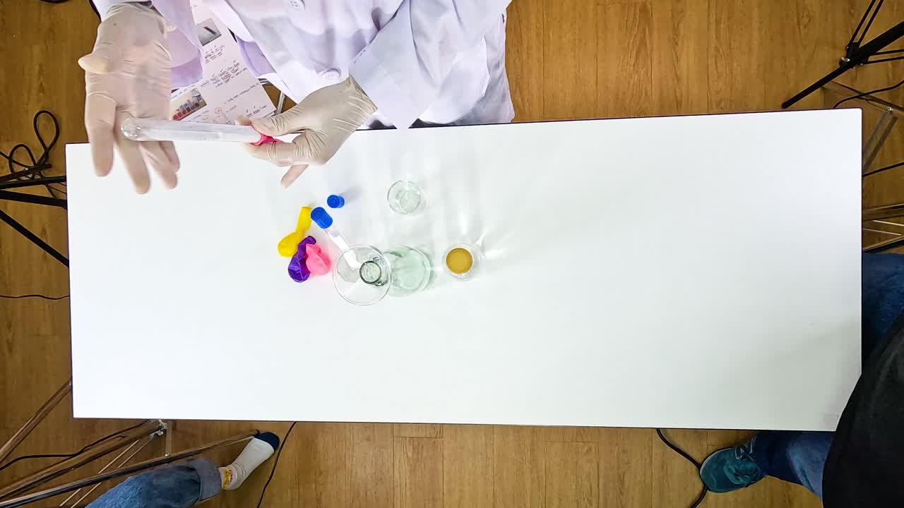 A science experiment inflating balloons using sodium bicarbonate and vinegar on a white table with overhead lighting