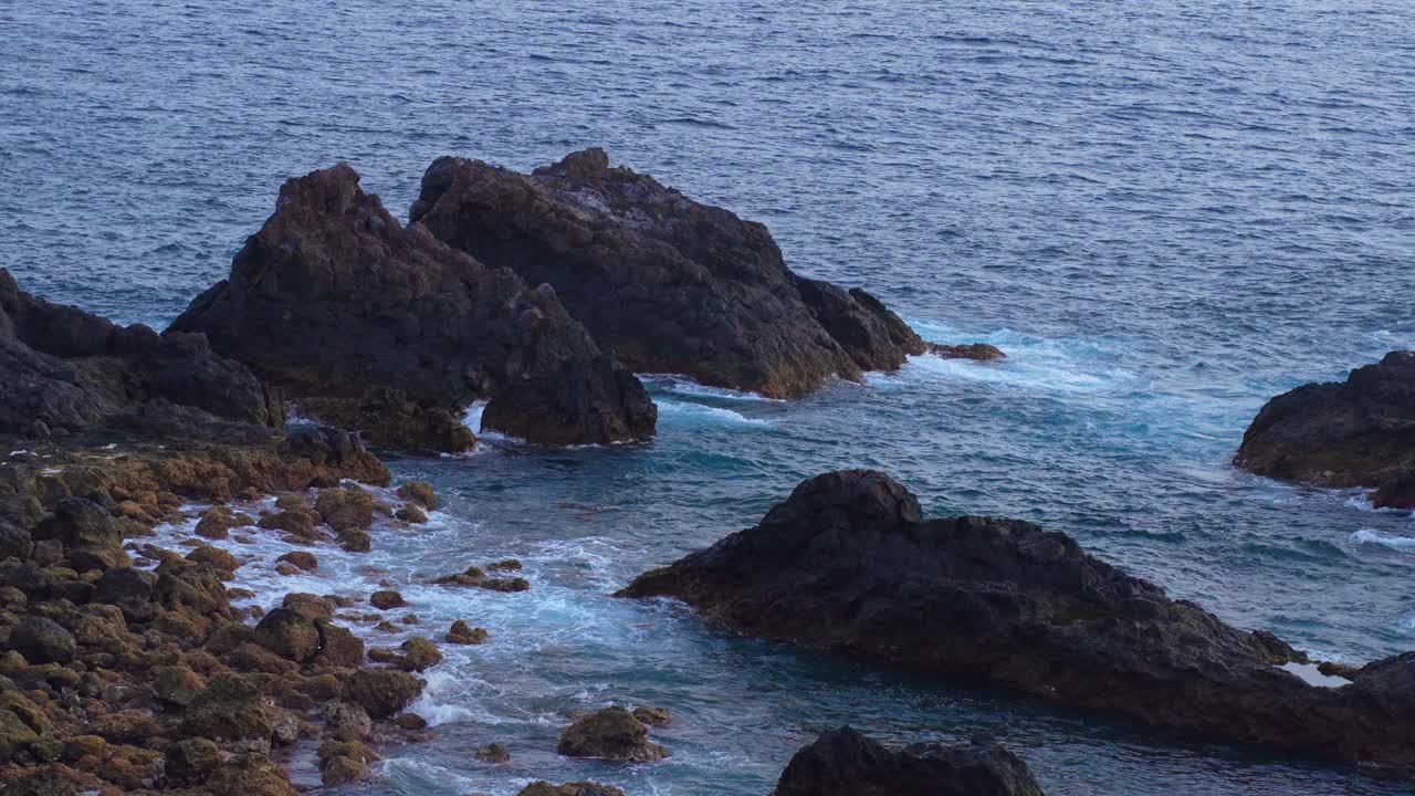 Formazioni rocciose in riva al mare con onde d'acqua provenienti dal mare delle Isole Canarie, Tenerife, rallentatore statico.