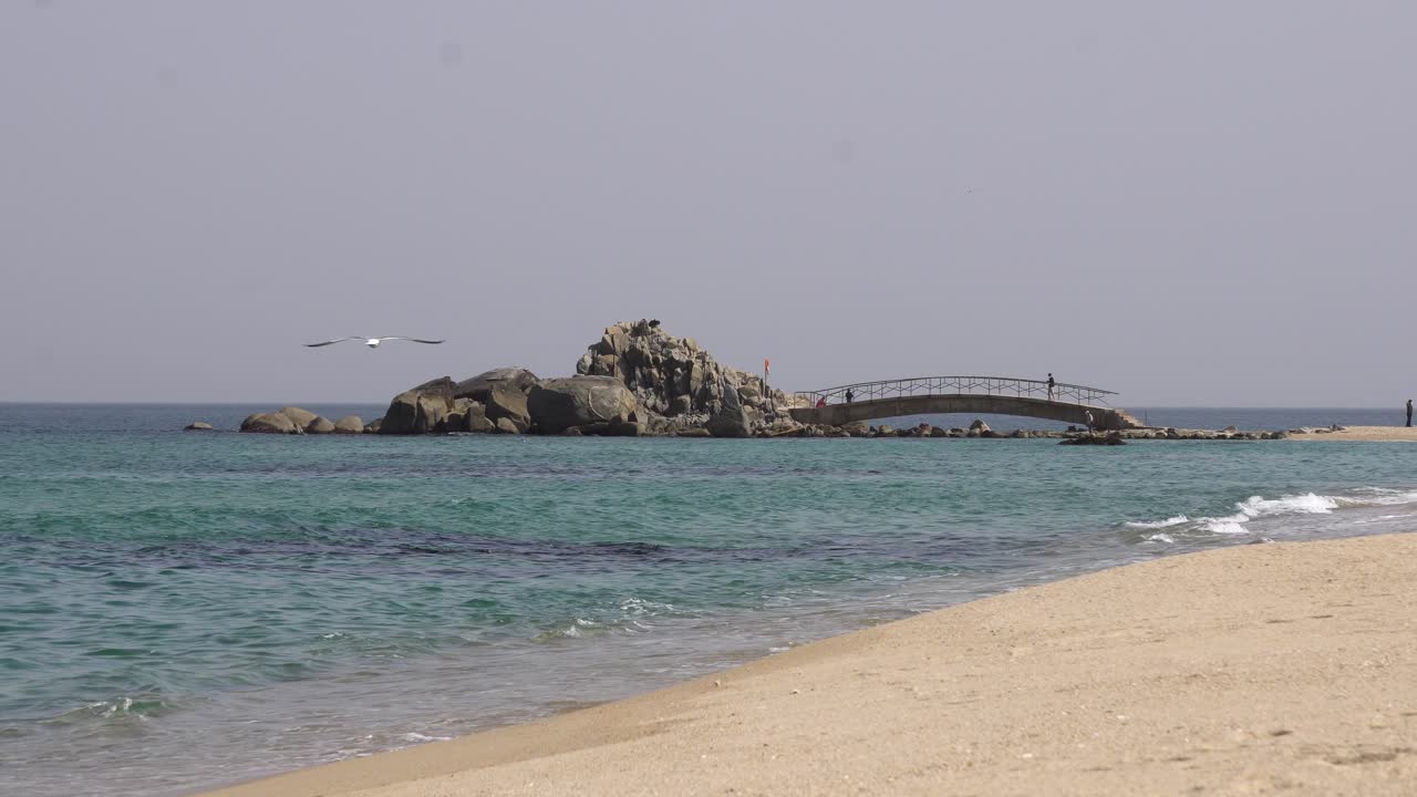 Serene Beach Scene with Bridge to Rocky Island