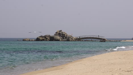 serene beach scene with bridge to rocky island