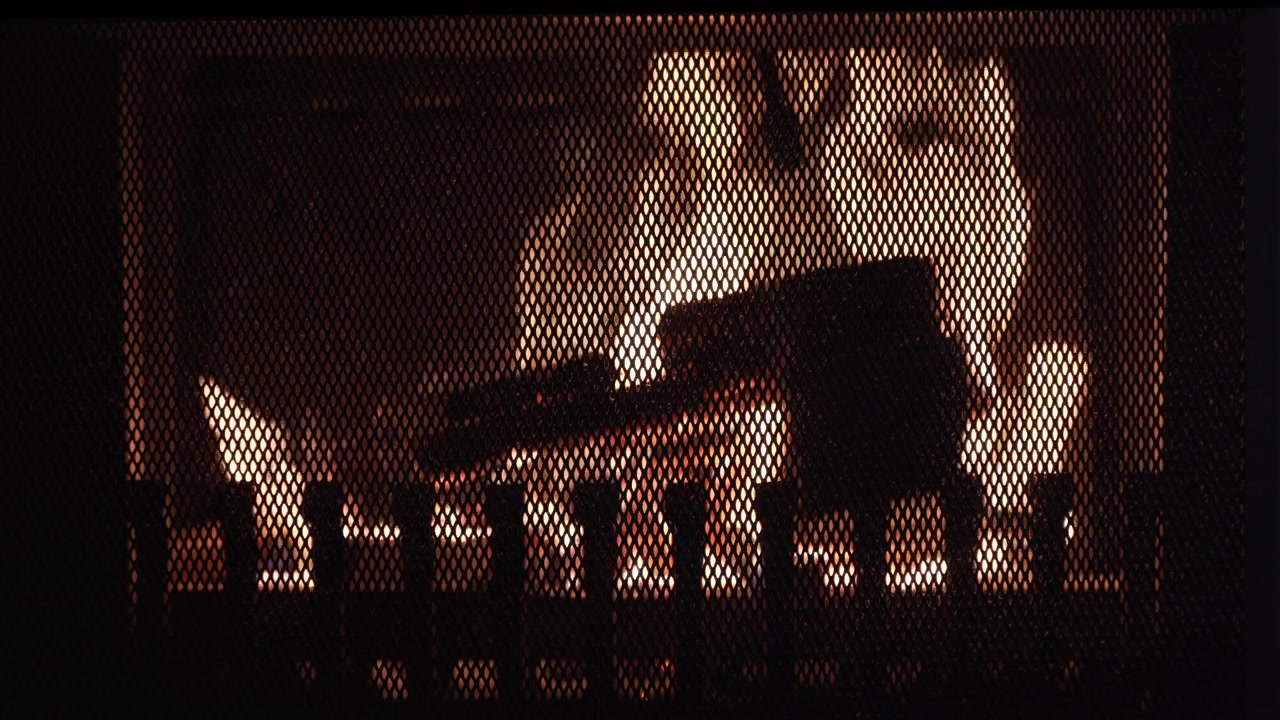 Steady shot of a zoomed in burning fireplace. Cosy and dark atmosphere.